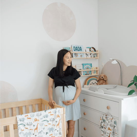 pregnant mom standing in baby nursery with wall decals
